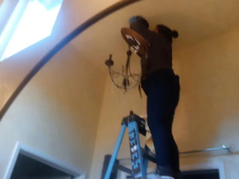 Electrician installing a chandelier in a Brook Highland residence